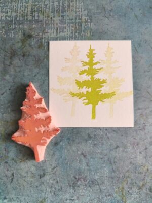 Ręcznie rzeźbiony stempel z motywem drzewa iglastego oraz odbitka w odcieniach zieleni, ilustracja leśna do scrapbookingu i prac kreatywnych.