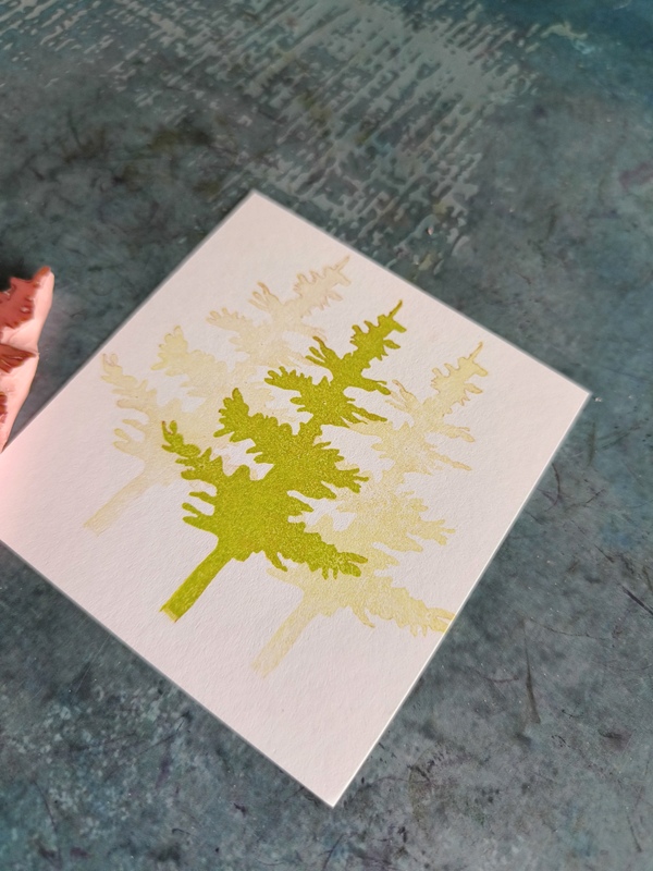 Ręcznie rzeźbiony stempel z motywem drzewa iglastego oraz odbitka w odcieniach zieleni, ilustracja leśna do scrapbookingu i prac kreatywnych.